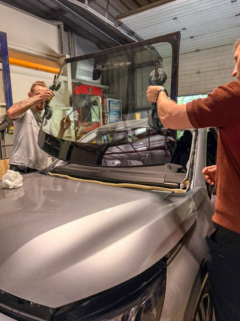 Dylan et Tristan travaillant en binôme pour ajuster le nouveau pare-brise.